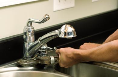 Highlands Ranch Plumbing technician tightens a kitchen sink